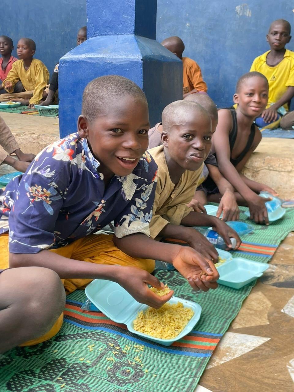 A smiling boy eating a meal at the orphan centre