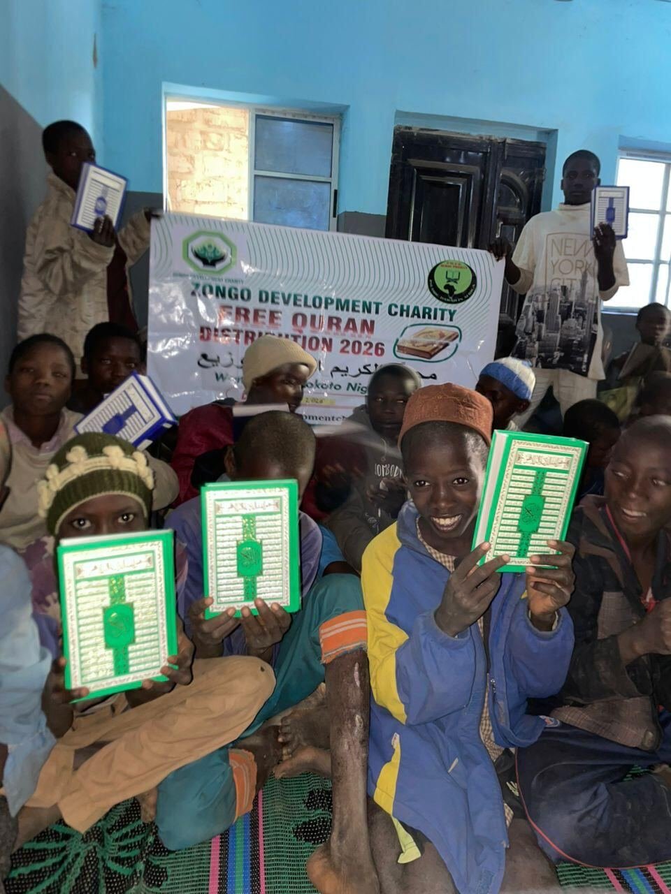 Children holding Qurans in front of the charity banner