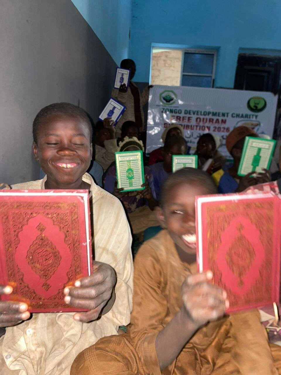 Two boys holding up their new Qurans